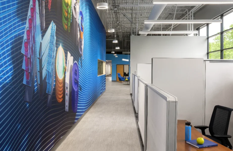 The interior of an office with cubicles lining a wall of large windows